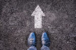 Feet and two arrows painted on an asphalt road